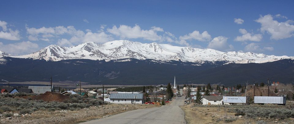 Snow-covered Mount Massive filling the sky behind a Leadville street and church steeple